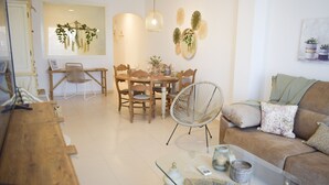Ein modernes Wohnzimmer mit einem Holzes Esstisch, Stühlen, einem Glastisch und einem Sofa.