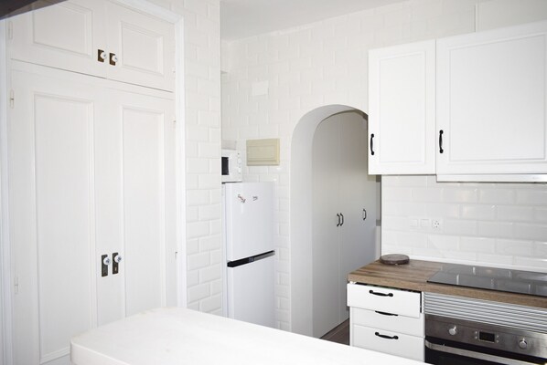 A modern kitchen with white cabinetry, a built-in oven, and a microwave. - Anacasa Planta Baja Marineta Bot PB2105 (Denia)