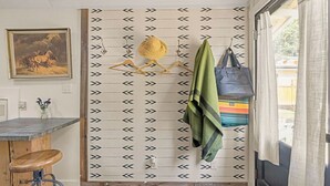 A room with a patterned wall, a painting, a bar area, and a view through a door. - The Arrow Cottage (Bend)