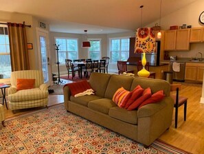 Cozy living space with a green sofa, striped armchair, and dining area for four.