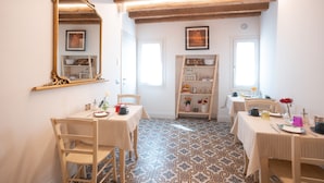 Un coin repas comprenant deux tables, des chaises, un miroir et une étagère ornée d’objets décoratifs.