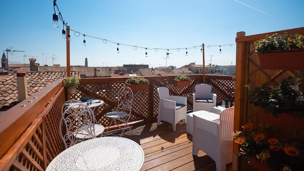 Une terrasse sur le toit, aménagée avec des espaces de détente en plein air, des guirlandes lumineuses et des plantes en pot.