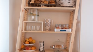 Une étagère en bois contenant divers objets, notamment des fruits, des bocaux et des objets décoratifs.