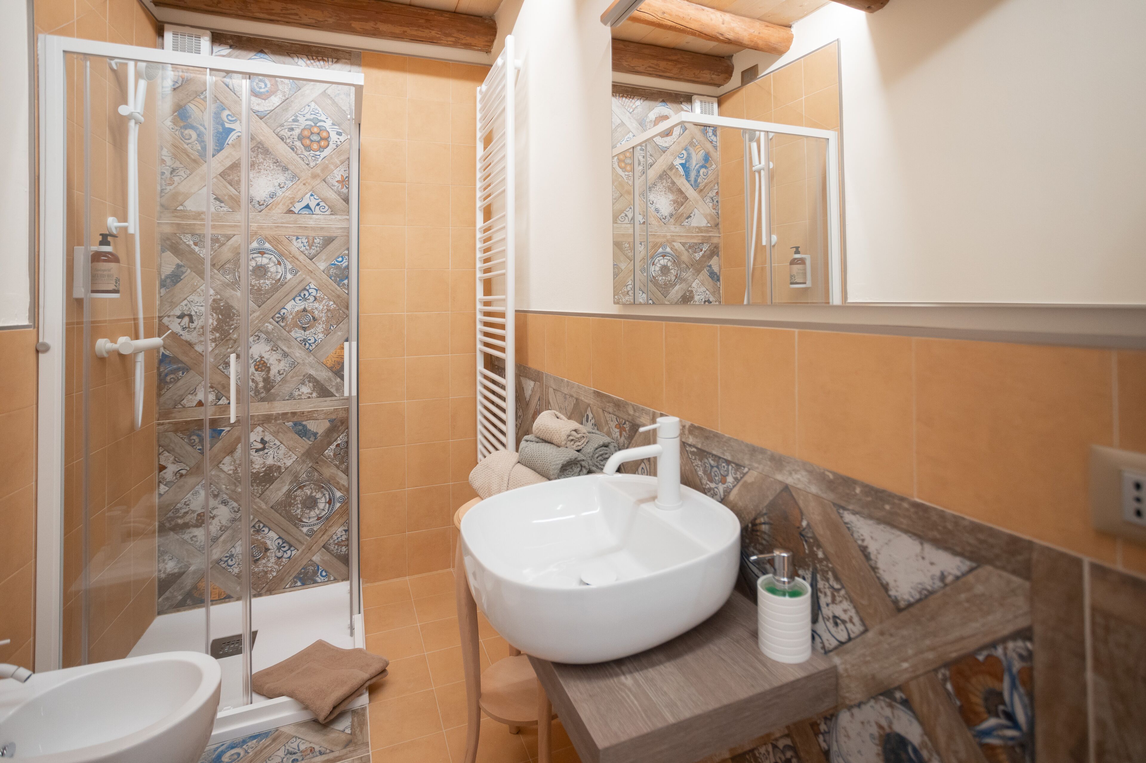 Een badkamer met een groot wit wastafelmeubel, een douchecabine van glas en een spiegel boven het wastafelmeubel.