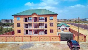 A multi-story building with a brick facade, a green roof, and a gated entrance. - Racapa Apartments (Santeo)