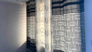 A room with patterned curtains and a ceiling light fixture. - Racapa Apartments (Santeo)