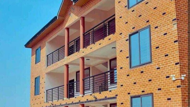 A multi-story building with a brick facade, balconies, and a covered entrance. - Racapa Apartments (Santeo)
