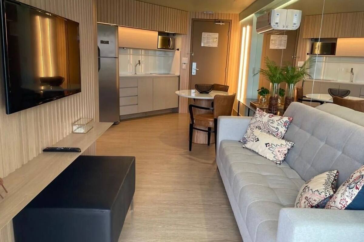 Ett modernt vardagsrum med en platt-TV, en soffa och en matplats med ett bord och stolar.