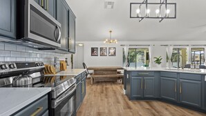 A modern kitchen with stainless steel appliances, wooden flooring, and a central island. - Luxury Corner Home, Arcade, Heated Pool & Spa. No extra fees. Pet Friendly. (Davenport)