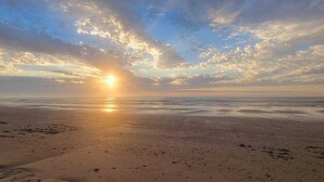 Une plage où le soleil se couche à l’horizon, créant une atmosphère paisible et sereine.