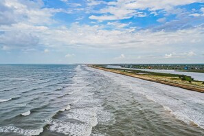 Eine Küstenansicht mit Strand und einer parallel zur Küste verlaufenden Straße.
