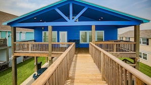 Une maison bleue avec une terrasse en bois et un porche abrité.