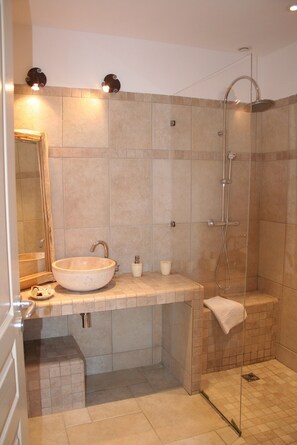 A modern bathroom with a large vessel sink, a glass-enclosed shower, and a mirror above the sink.