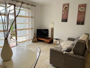Ein Wohnzimmer mit einer Couch, einem Fernseher, einem Couchtisch und einer Vase mit Zweigen.
