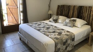 Une chambre à coucher avec un lit, des oreillers, une table de chevet, une lampe et une tête de lit en bois.