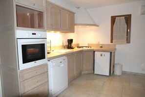 Una cocina compacta con horno integrado, lavavajillas y un refrigerador pequeño.