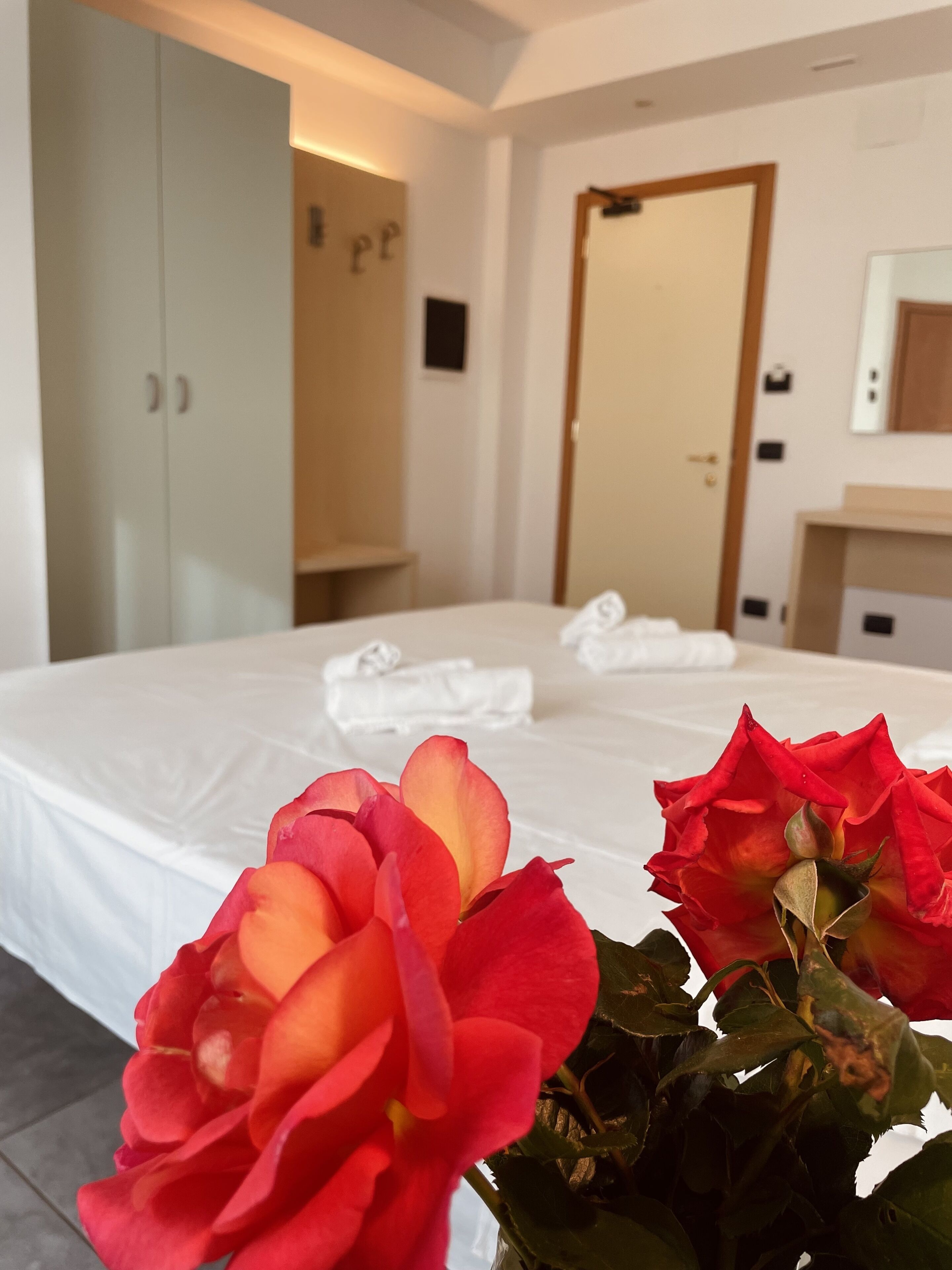 Une chambre d’hôtel avec un lit bien fait, une armoire et un miroir au mur.
