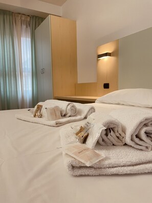 A hotel room with a bed, a wardrobe, and a wall-mounted light. - Hotel Grecale - Venturina Terme (Campiglia Marittima)