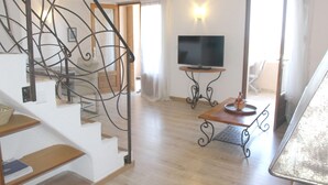 A spacious living area with a staircase, a flat-screen TV, and a dining table. - Apartment-Standard-Ensuite with Shower-Sea View-T3 (Porto-Vecchio)