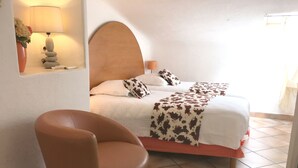 A bedroom with a bed, a chair, a lamp, and a wall-mounted shelf with a vase. - Apartment-Standard-Ensuite with Shower-Sea View-T3 (Porto-Vecchio)