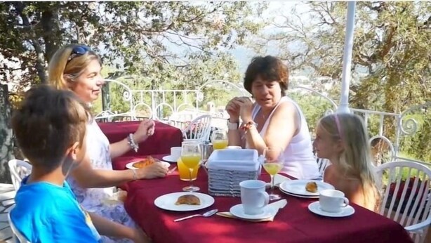 A group of people seated at an outdoor table with a red tablecloth, enjoying breakfast. - Apartment-Standard-Ensuite with Shower-Sea View-T3 (Porto-Vecchio)