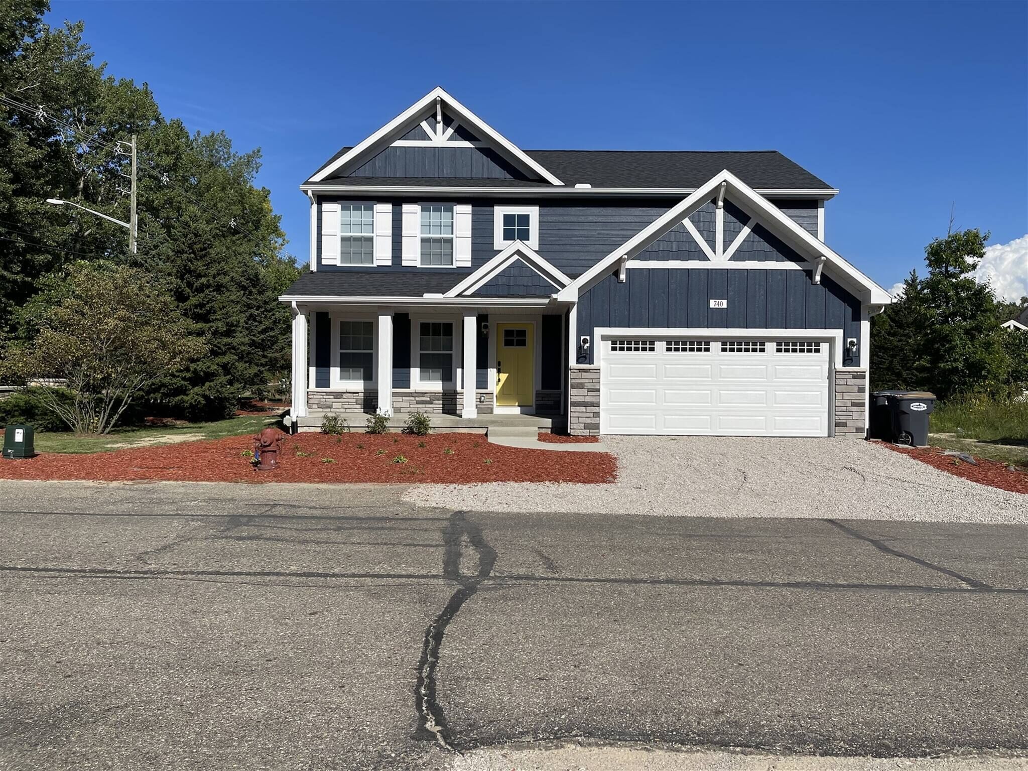 Charming two-story home with welcoming front porch, bright exterior, and spacious attached garage.