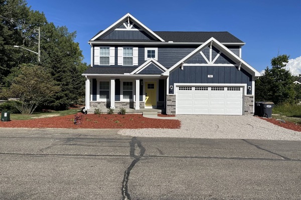 Charming two-story home with welcoming front porch, bright exterior, and spacious attached garage.