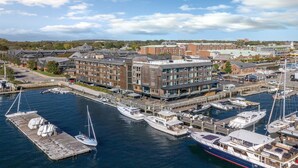 A marina with boats docked, a building with multiple floors, and a dock area.