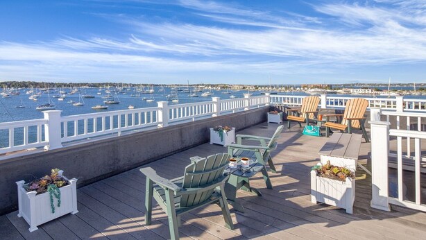 A deck with outdoor seating, overlooking a marina with numerous boats.