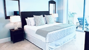 A bedroom with a bed, nightstands, a ceiling fan, and a large window. - Cozumel-Beautiful 2 bedroom ocean view condo (San Miguel de Cozumel)