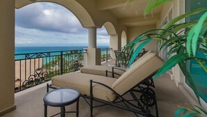 A balcony with a view of the ocean, beige lounge chairs, a small table, and a potted plant. - Cozumel-Beautiful 2 bedroom ocean view condo (San Miguel de Cozumel)
