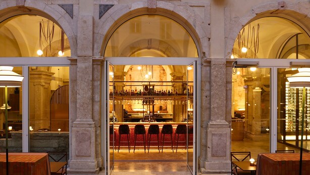 A bar area with a counter, multiple chairs, and a stone column structure. - Convent Square Lisbon, Vignette Collection by IHG (Lisbon)