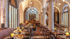 A spacious restaurant with high ceilings, arched windows, and a central chandelier. Tables are set with candles and glassware. - Convent Square Lisbon, Vignette Collection by IHG (Lisbon)