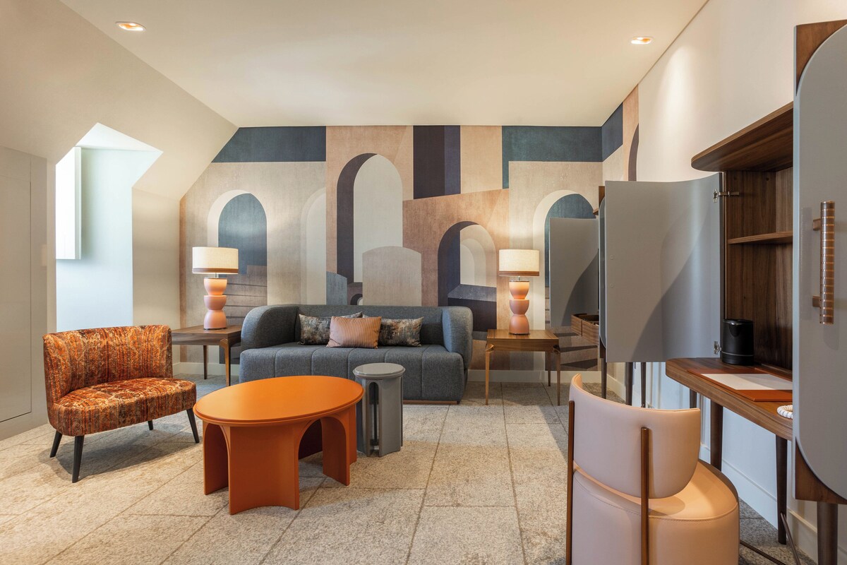 A modern living room with a sofa, armchairs, a coffee table, and a TV stand.