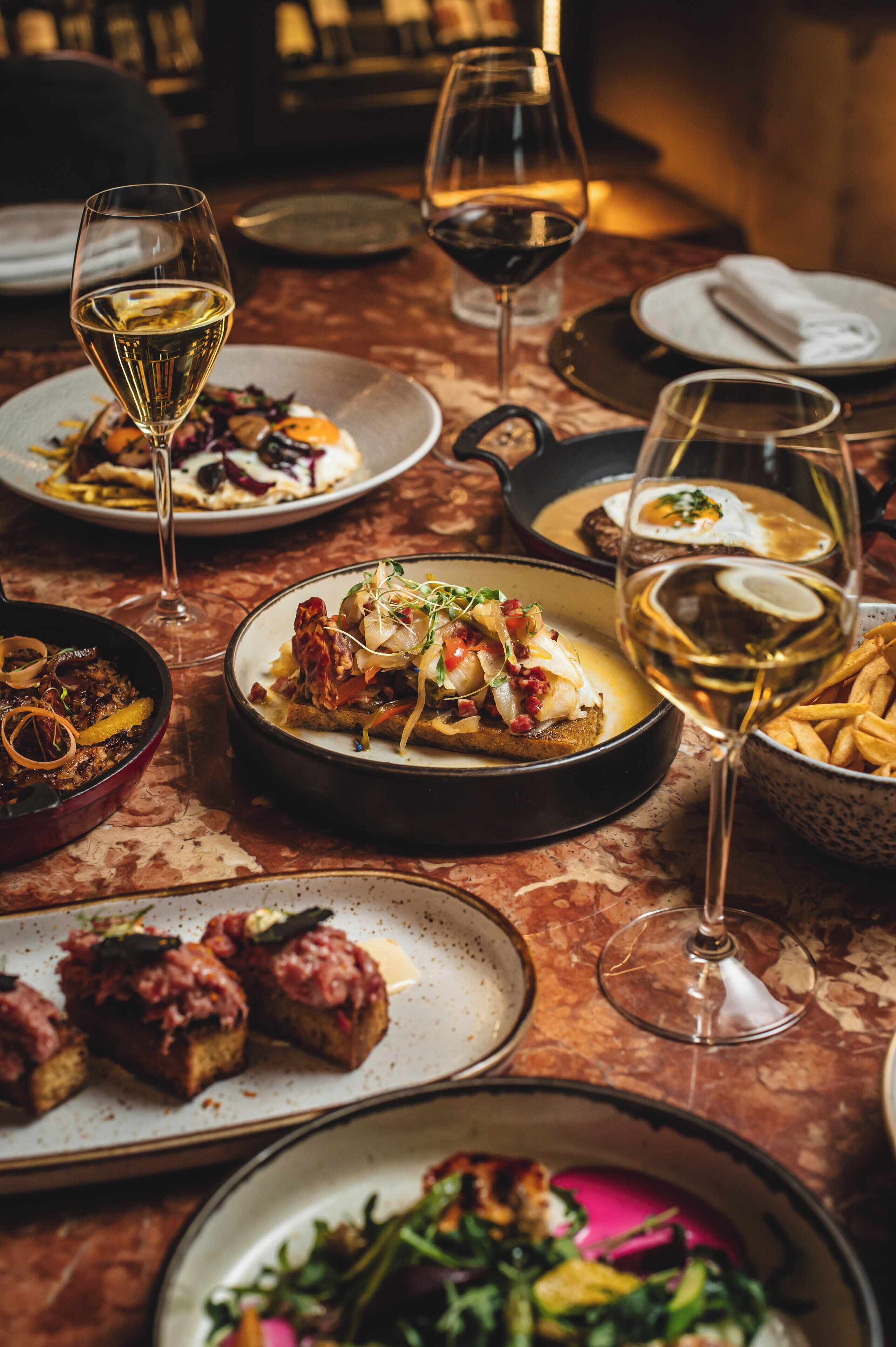A dining table with various dishes and wine glasses.