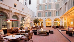 A spacious courtyard with outdoor seating, a central fire feature, and a modern building facade. - Convent Square Lisbon, Vignette Collection by IHG (Lisbon)