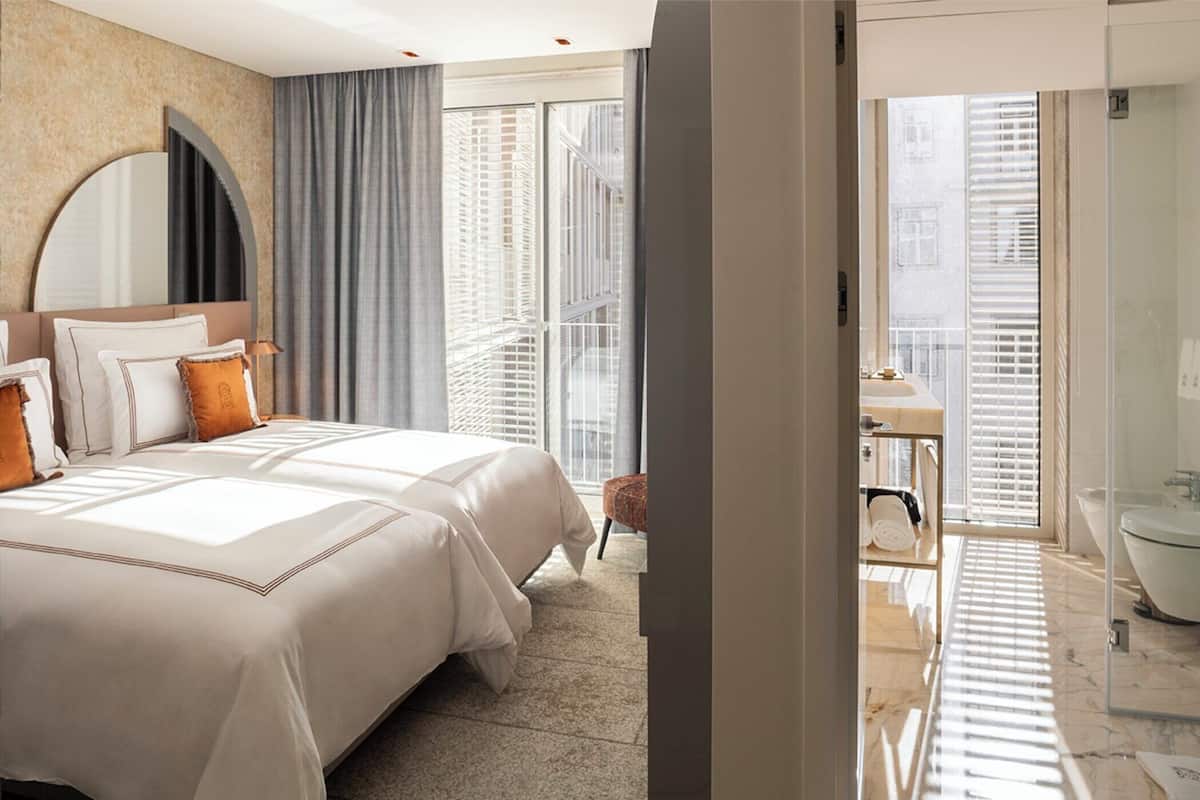 A hotel room with a large bed, a sitting area with a view, and a bathroom with a bathtub.
