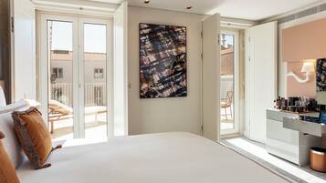 A hotel room with a large bed, a bathroom with a mirror and toiletries, and a balcony with outdoor furniture.