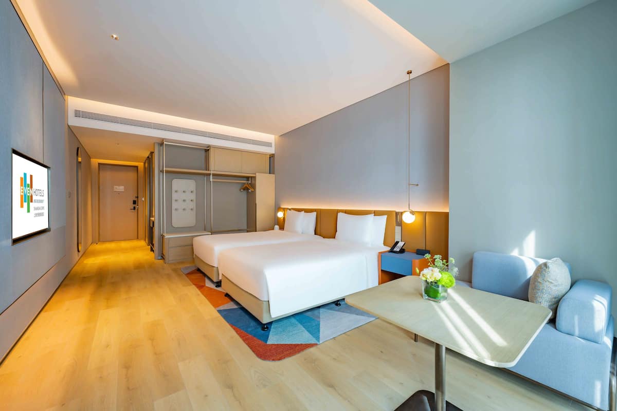 Una habitación de hotel moderna con una cama grande, un sofá, una mesita y un escritorio.