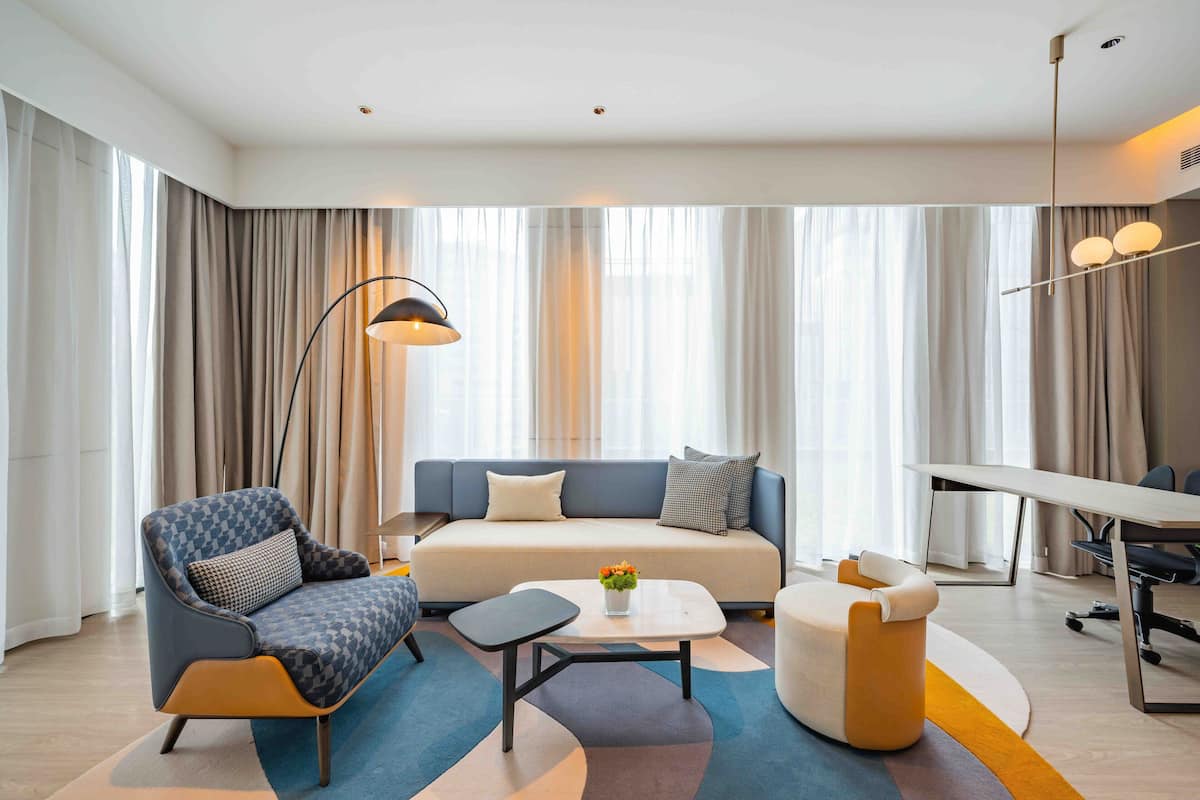 A modern living room with a sofa, armchair, coffee table, and a dining area with a table and chairs.