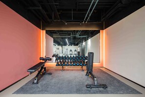 A gym with exercise equipment, including dumbbells and benches, and a carpeted floor.