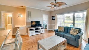 A living room with a sofa, TV, wooden coffee table, and a ceiling fan. - Golf, Swim & Unwind at Bright Myrtle Beach Condo! (Myrtle Beach)