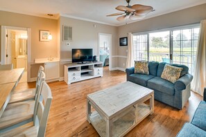 A living room with a sofa, television, wooden coffee table, and a ceiling fan.