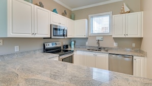 A kitchen with white cabinets, a granite countertop, a microwave, a stove, and a dishwasher. - Golf, Swim & Unwind at Bright Myrtle Beach Condo! (Myrtle Beach)