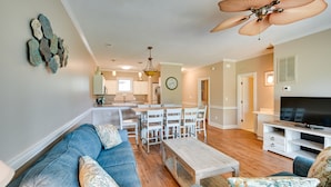 A spacious living room with a blue sofa, a wooden coffee table, and a television. - Golf, Swim & Unwind at Bright Myrtle Beach Condo! (Myrtle Beach)