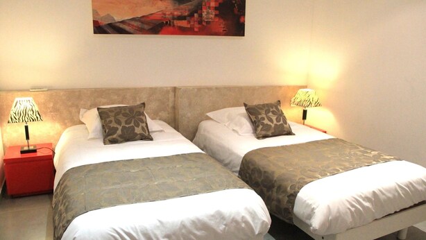 Une chambre d’hôtel avec deux lits, chacun étant équipé d’un oreiller et d’une lampe.