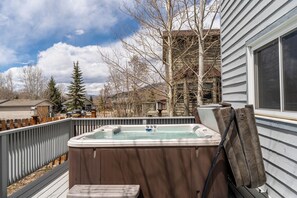A hot tub on a deck with a wooden fence, a wooden bench, and a view of a house and trees. - Stand-alone Mountain Home, Private Hot Tub and Deck, Mountain Views #34 by Summit County Mountain Retreats (Silverthorne)