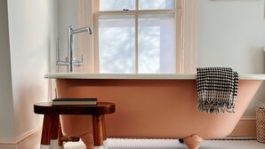 Een badkamer met een vrijstaand bad, een houten kruk, en een vloer waarop 'peachy' staat in een patroon.
