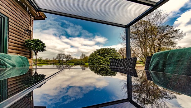A modern room with a large glass window reflecting the sky and trees.