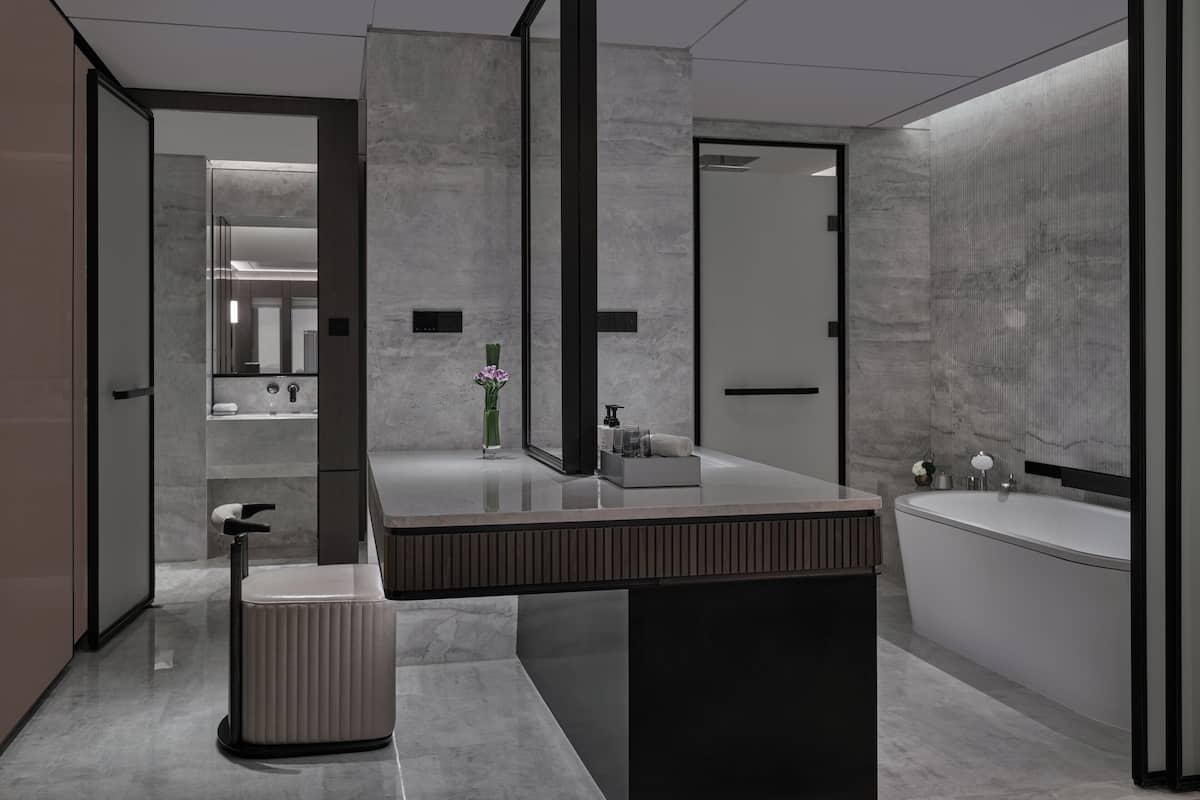 Un baño moderno con un espejo grande, un tocador con lavabo y una bañera.